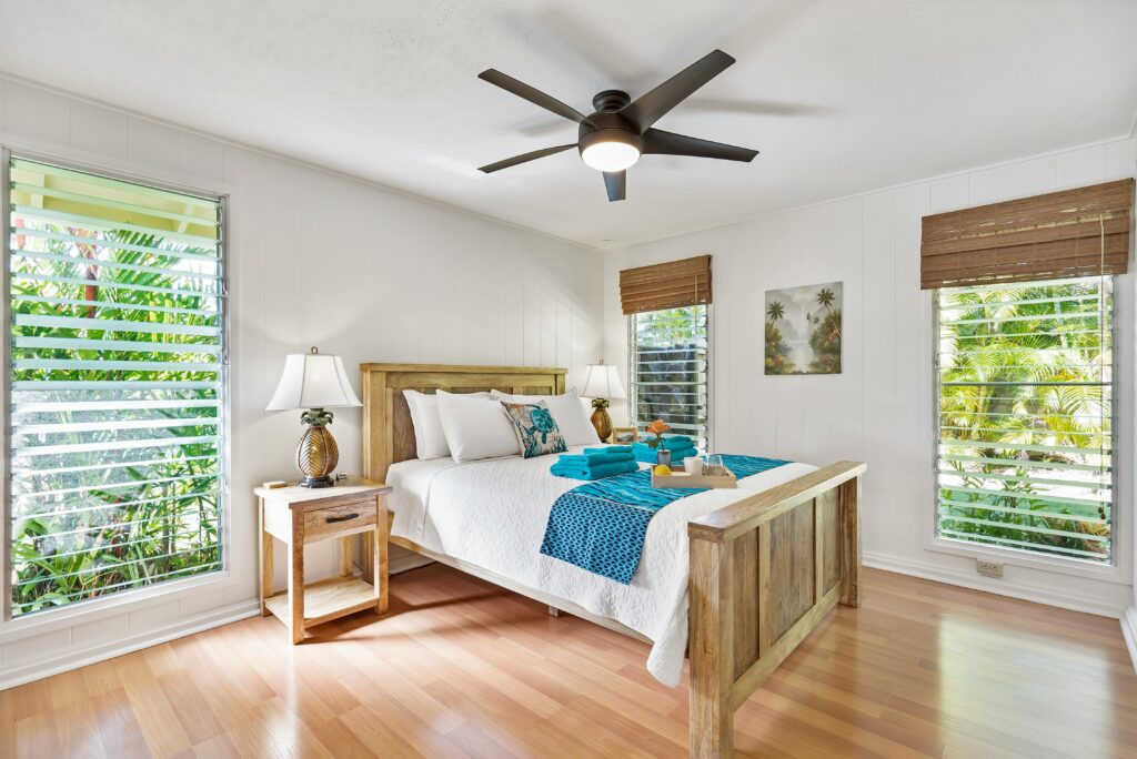 Sunny tropical bedroom with wooden furniture, teal accents, and lush greenery views.